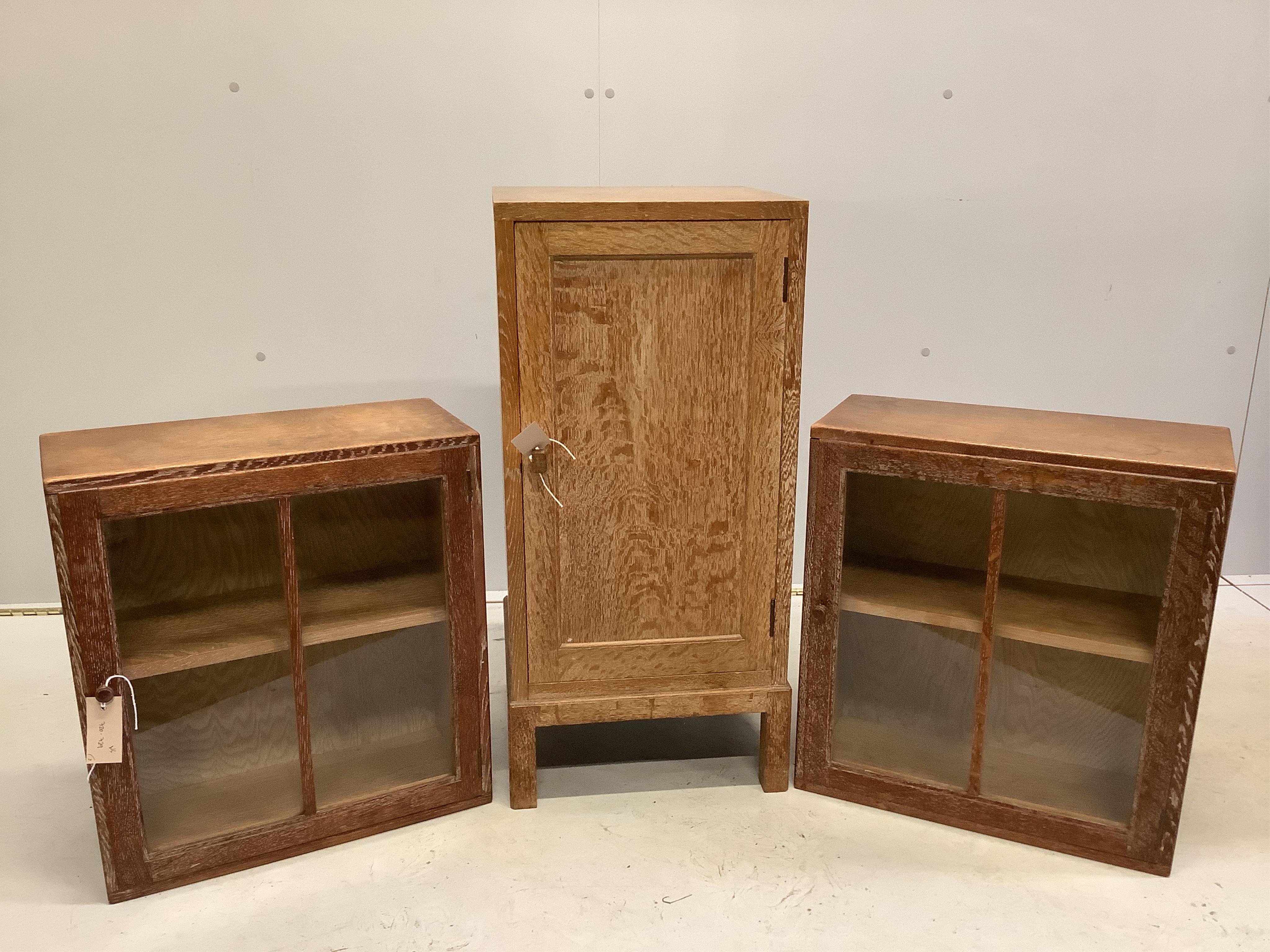 Heal & Son Ltd. A pair of weathered oak wall cabinets, width 45cm, depth 21cm, height 50cm together with a Heals oak bedside cupboard, width 36cm, height 76cm. Condition - fair to good